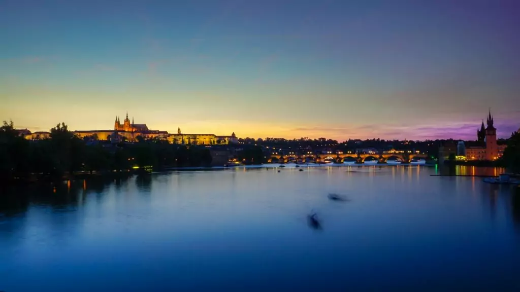 silhouette of city between calm water and golden sky